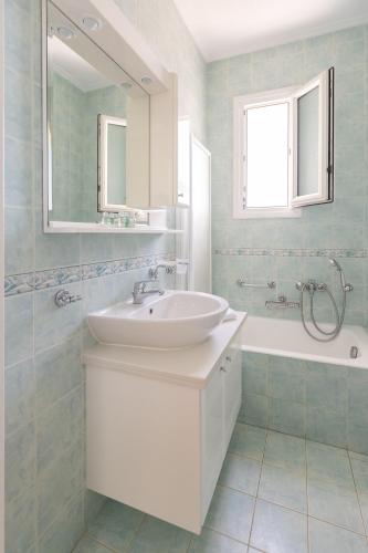 a bathroom with a sink and a mirror and a tub at Chios Seafront Luxury Villa with Pool in Chios
