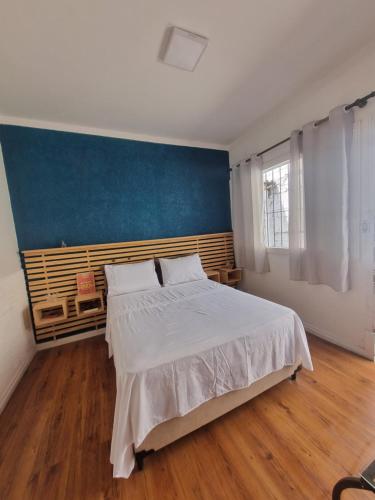 a bedroom with a large bed and a blue wall at Loft em Butantã, próximo a USP in São Paulo