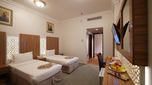 a hotel room with two beds and a table at ASTONEAST TAIBA Hotel in Medina