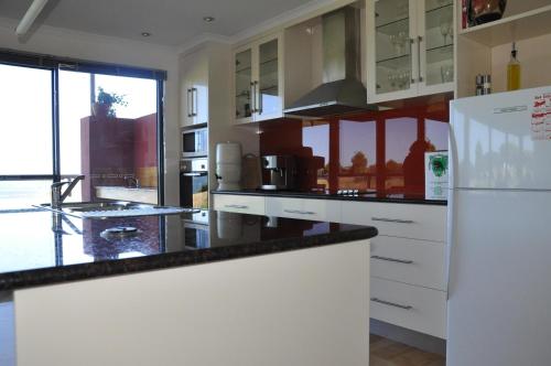 a kitchen with white cabinets and a white refrigerator at Black Rock Retreat in Howth