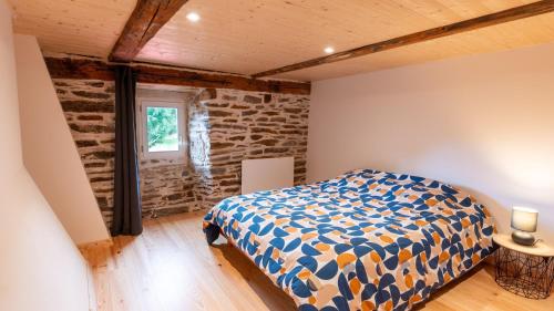 a bedroom with a bed and a stone wall at Gîte de montredon in Cubières