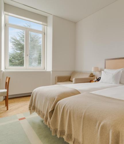 two beds in a room with a window at Pousada da Serra da Estrela in Covilhã