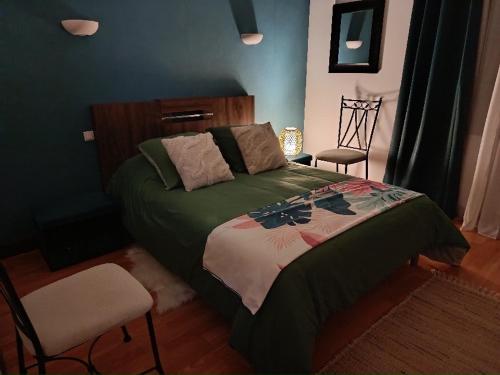 ein Schlafzimmer mit einem Bett mit grüner Bettdecke und zwei Stühlen in der Unterkunft Bienvenue ! in Moissac