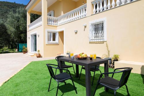 a patio with a table and chairs on grass at The Olive Grove Cottage by Konnect - 2,5km from Ipsos in Ipsos