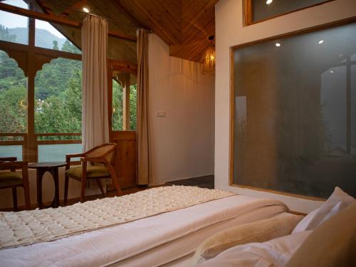 a bedroom with two beds and a large window at Kuhama Private Mountain Chalet Naggar in Nagar