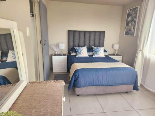 a bedroom with a bed with blue sheets and blue pillows at VitaminSea in Mossel Bay