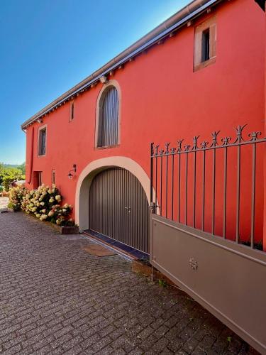 a red building with a gate next to a brick road at Eschette Retreat in Rambrouch
