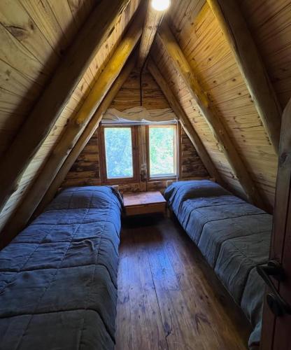 a bedroom in a log cabin with two beds at Cabañas de montaña Triskel in Aluminé