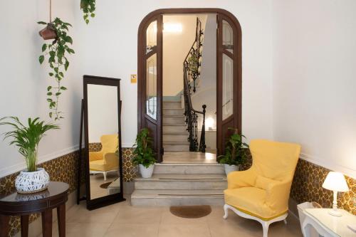 a hallway with stairs and a yellow chair and mirror at ABCyou Bed&Breakfast in Valencia