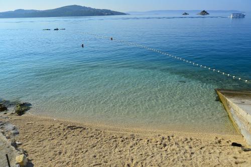 a beach with people swimming in the water at Happy Camp mobile homes in Camping Amadria Park Camping Trogir in Seget Vranjica
