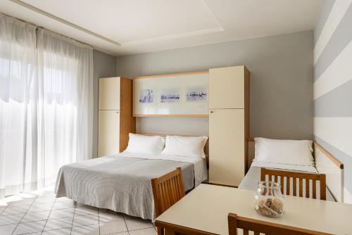 a bedroom with two beds and a desk and a window at Hotel Sport & Residenza in Cesenatico