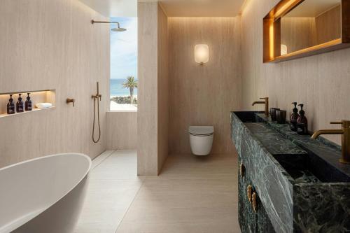 a bathroom with a tub and a toilet and a sink at Morea House, Autograph Collection in Cape Town