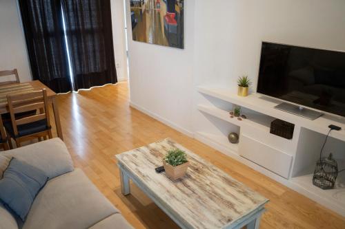 a living room with a couch and a tv at BONITO APARTAMENTO a 200 metros del centro de Sevilla con piscina y parking gratis in Seville