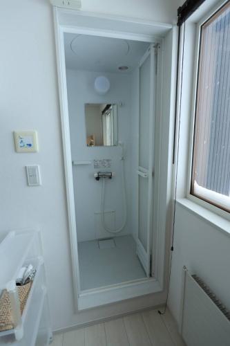 a white bathroom with a shower with a mirror at バーニングハーツ in Asahikawa