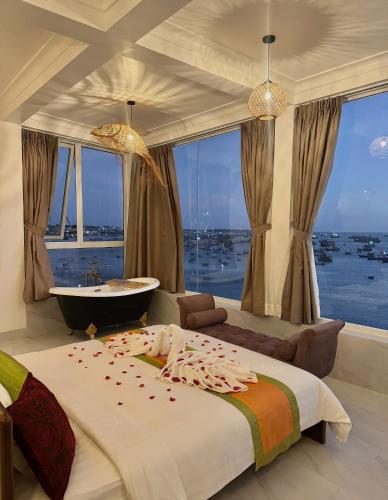 a bedroom with a large bed and a tub and windows at Bay View Resort & Villas Mũi Né in Phan Thiet