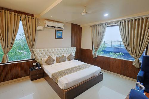 a bedroom with a large bed and two windows at Hotel Leaf Inn in Lucknow