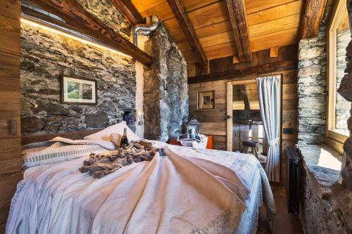 a bedroom with a bed in a stone wall at Maison La Saxe in Courmayeur