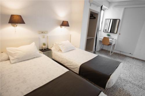 a hotel room with two beds and a desk at Hostal On Dormire Valencia in Valencia