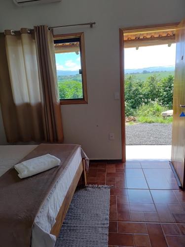 a bedroom with a bed and a large window at Chalésforquilha in Delfinópolis