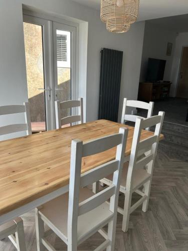 a wooden table with four white chairs around it at Spacious Three Bedroom Flat in Filey Town Centre with Workspace in Filey