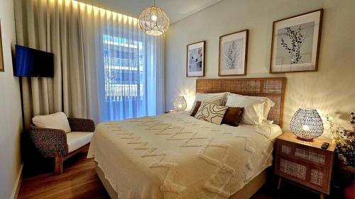 a bedroom with a bed and a chair and a window at Sweet Horizon in Quarteira