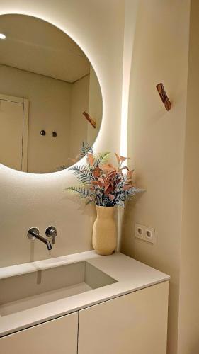 a bathroom with a sink and a vase with a plant at Sweet Horizon in Quarteira