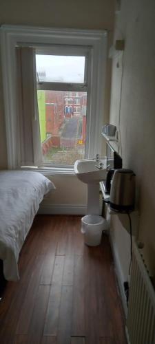a bedroom with a bed and a sink and a window at The Osprey Hotel in Blackpool