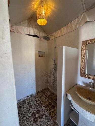 a bathroom with a sink and a mirror at Desert Luxury Camp Erg Chigaga in El Gouera