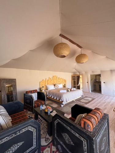 a bedroom with a bed and two couches at Desert Luxury Camp Erg Chigaga in El Gouera