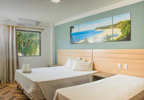 a room with two beds and a painting on the wall at Porto Mar Hotel in Porto Seguro