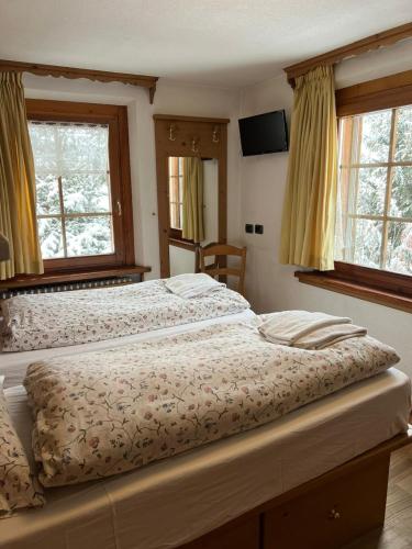 a bedroom with two beds and two windows at Chalet Del Sole per gruppi in Livigno