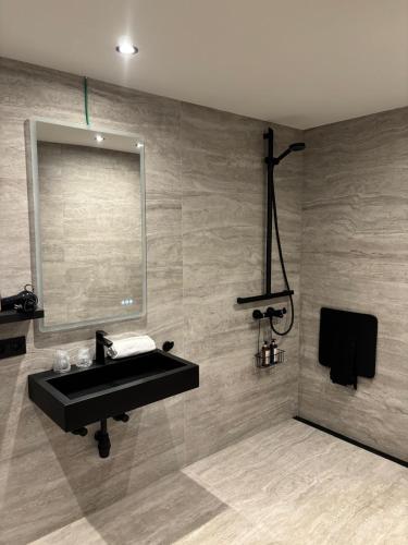ein Badezimmer mit schwarzem Waschbecken und Spiegel in der Unterkunft Hotel Cortina in Wevelgem
