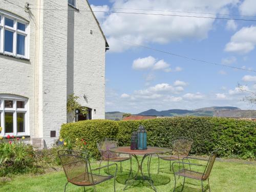 a table and chairs in the yard of a house at Upper Broughton Farm Cottage in Snead