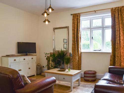 a living room with a couch and a tv at Upper Broughton Farm Cottage in Snead