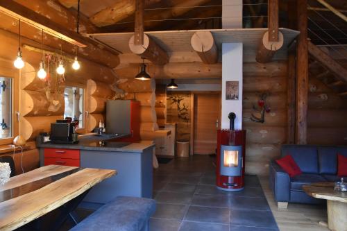 a kitchen and living room with a fireplace in a log cabin at Chalet Enzian Bayerwald in Arnbruck