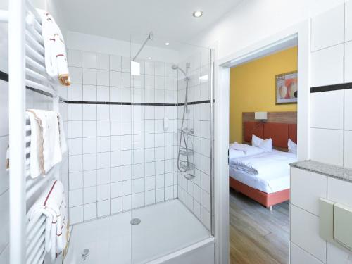 a bathroom with a walk in shower next to a bed at Hotel Kronprinz in Bad Salzdetfurth