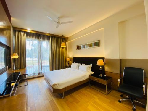 a bedroom with a bed and a desk and a chair at The Manak Bagh in Sehore