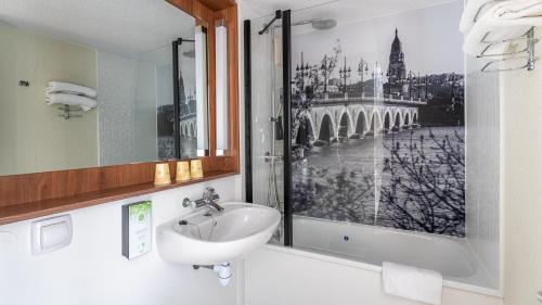 a bathroom with a sink and a picture of a bridge at Campanile NATURE - Bordeaux Lac in Bordeaux