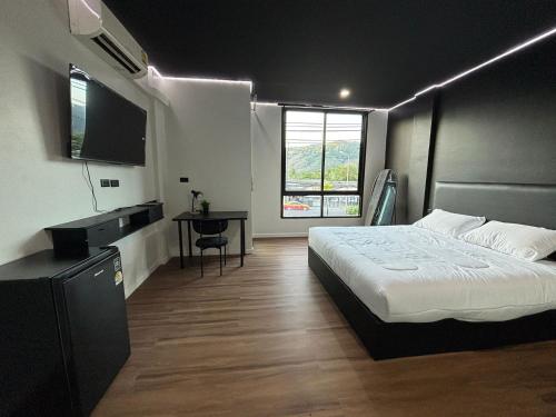 a bedroom with a bed and a flat screen tv at Atrium Kathu Hotel in Ban Kathu (1)