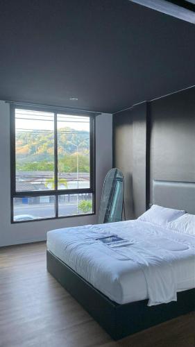a bedroom with a bed and a large window at Atrium Kathu Hotel in Ban Kathu (1)