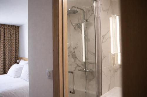 a shower with a glass door in a bedroom at Geographotel Paris-Roissy CDG Airport in Le Mesnil-Amelot