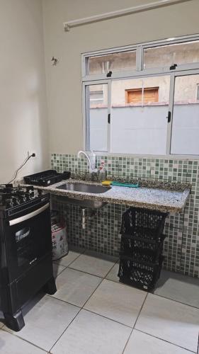 a kitchen with a sink and a stove and a window at Casa Itanhaém Praia Cibratel in Itanhaém