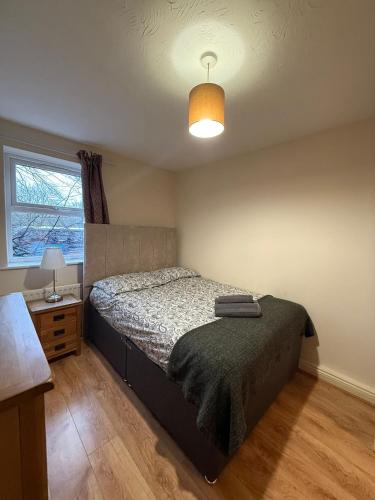 a bedroom with a bed and a lamp and a window at Beaumont Court in Coventry