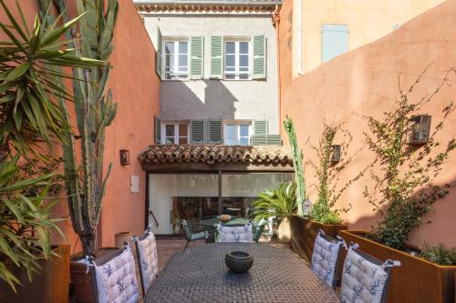 an outdoor patio with a table and chairs and a building at La Maison du Prince in Grimaud