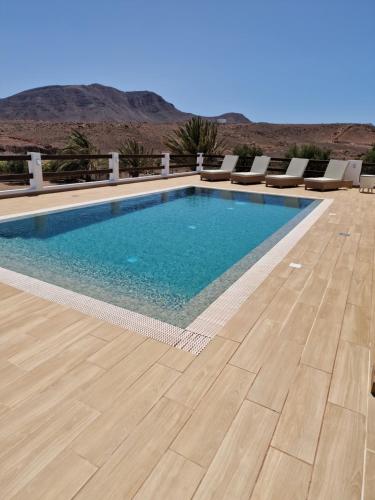 a swimming pool with a wooden floor and mountains in the background at Casa Abuela Serapia in Tuineje