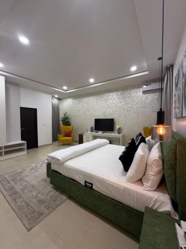 a large bedroom with a large bed and a tv at Nouveau Apartment in Abuja