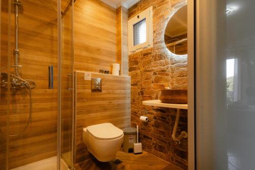 a bathroom with a toilet and a glass shower at Rizos Bay Sarakiniko in Sarakiniko