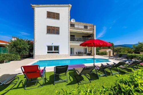 a villa with a swimming pool and a red umbrella at Villa Olivia Trogir in Trogir