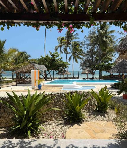 a view of a pool with palm trees and the ocean at MANOLO Beach Resort in Uroa