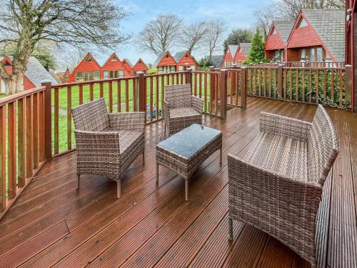 a deck with wicker chairs and tables and a fence at Lodge 64 in Kingsdown